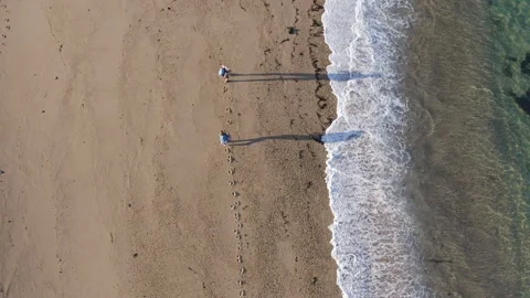 4K top-down view of couple walking along sandy beach washed by Atlantic Ocean wa Video stock 327250952