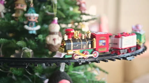 4K Toy train running on circular track around decorated christmas tree Stock Footage 334920427