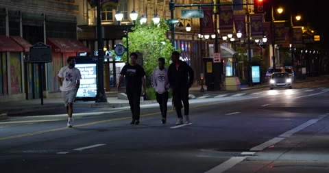 4K TRACKING SHOT OF FOUR YOUNG MEN WALKING DOWN LOOTED STREET AFTER PROTEST Stock Footage 132603099