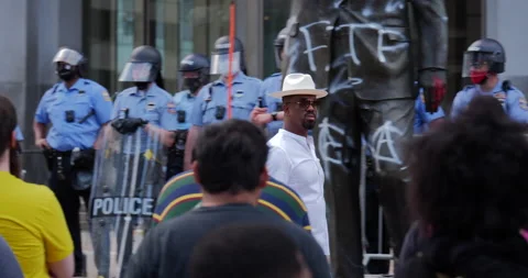 4K TRACKING SHOT OF PROTEST LEADER IN FRONT OF COPS AND VANDALIZED STATUE Stock Footage 131458861