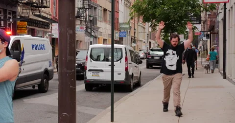 4K TRACKING SHOT OF PROTESTOR WITH HANDS UP AND LONG LINE OF POLICE CARS Stock Footage 132597686