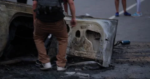 4K TRACKING SHOT OF PROTESTOR KICKING A BURNED CAR AT THE GEORGE FLOYD PROTEST Stock Footage 131460153