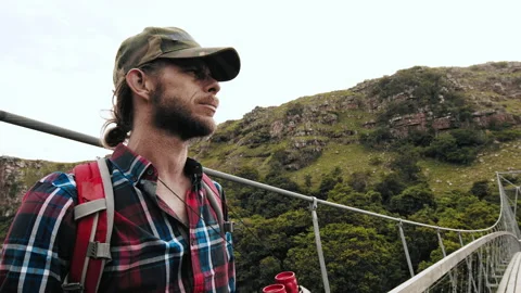 4k of trekker looking with binoculars while on wood sespention footbridge on wal Stock Footage 199621024