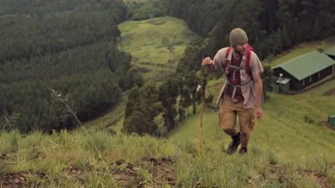 4k trekker walking away from log cabin to start hiking in green mountain range w Stock Footage 199619016