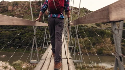 4k of trekker walking with walking stick on wood sespention footbridge on walkin Видео 199621035