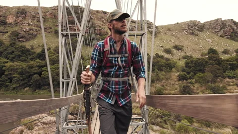 4k of trekker walking with walking stick on wood sespention footbridge on walkin 库存影片 199621047