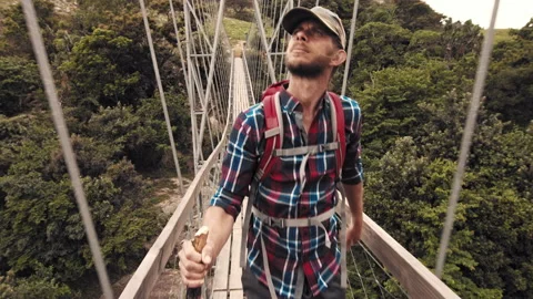 4k of trekker walking with walking stick on wood sespention footbridge on walkin Stock Footage 199621100