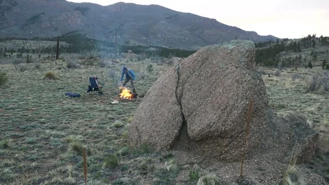 4K Twilight Hour Man with Axe next to Fire in Colorado Mountains Stock Footage 107633833