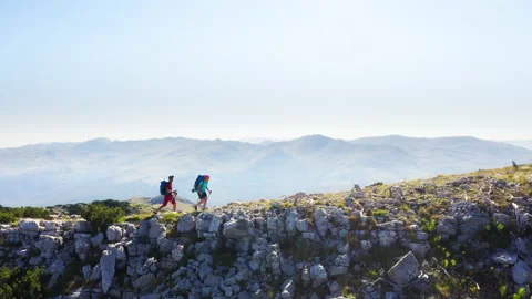 4k two backpackers walking by mountain ridge on sunny day with hiking poles Stock-Footage 153113226