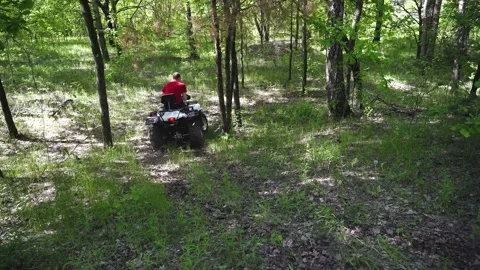 4K. Two guys on ATVs ride along a forest road, then turn down the hill. Stock Footage 139884570