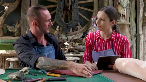 4K, Two handcrafted leather craftsmen are sitting discussing how make Stock Footage 237380406