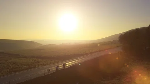 4k Two hikers walk toward sunset on lonely road in beautiful landscape Stock Footage 105403816