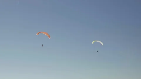 4K - Two paragliders flying next to each other in front of a blue sky in slo-mo Stock Footage 114063166