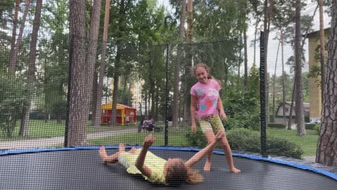 4k Two small girls jumping on a trampoline in a park. Stock Footage 168987325
