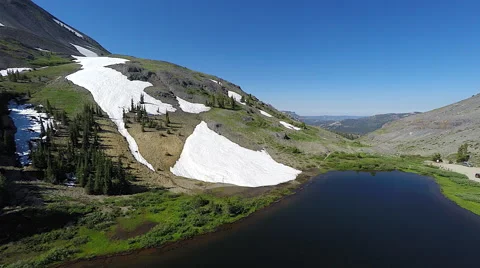 4k UHD Aerial tracking back from snow capped mountain with lake below Stock Footage 66561793