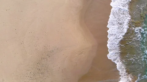 4k UHD aerial view of waves splash motion over multicolored sandy sea coast Stock Footage 104001114