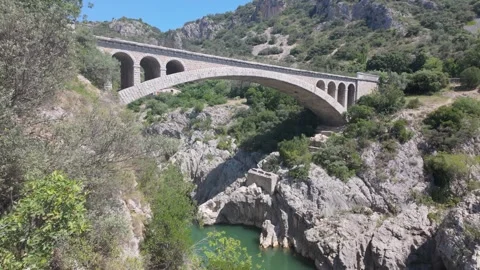 4K UHD dynamic handheld shot descending from stone arch bridge to river canyon Stock-Footage 347134145