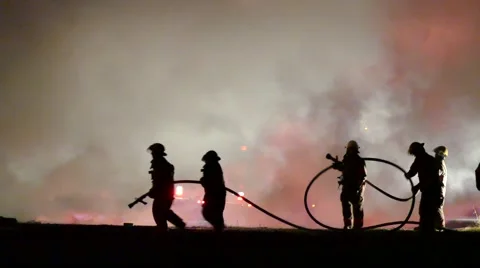 4K UHD - Firemen moving closer to source of fire with water hoses Video stock 50561914