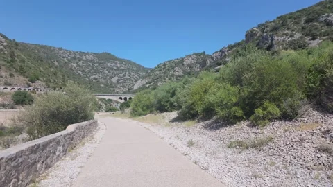 4K UHD handheld tracking shot of paved mountain path with stone wall and viaduct Stock-Footage 347127340