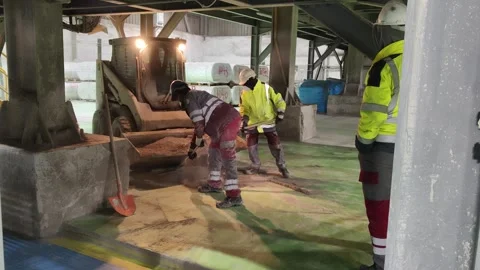 4K UHD: Industrial Workers Cleaning Cement Dust Near Caterpillar Skid Steer Stock Footage 332015106