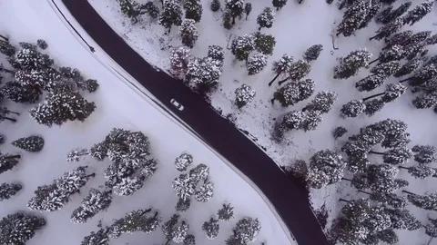 4K UHD overhead drone view of cars traveling down snowy mountain road Видео 75541632