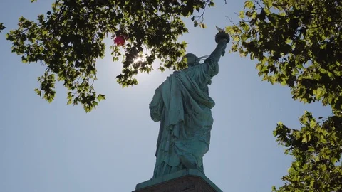 4K Unique Perspective of the Statue of Liberty Through Trees with Sunlight Stock Footage 123395801