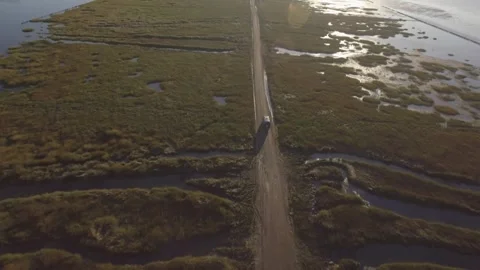 4K Van drives away into the sun for a new adventure on a small strip of land Vídeo Stock 249019173