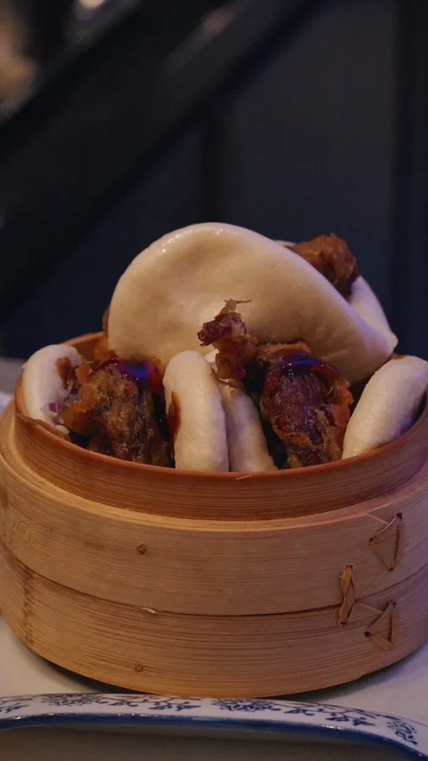 4K vertical close up chef garnishing duck bao with herbs in bamboo container Stock Footage 315990538
