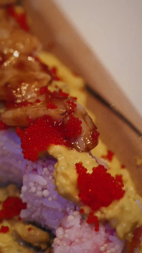 4K vertical close up Chef topping scallop on tobiko mango guacamole sushi roll Stock Footage 315565004