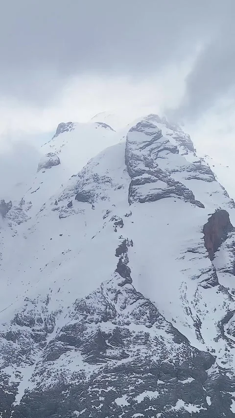 4K vertical drone orbit of snowy Aladaglar mountains with fog clouds, snowfall Stock Footage 336449797