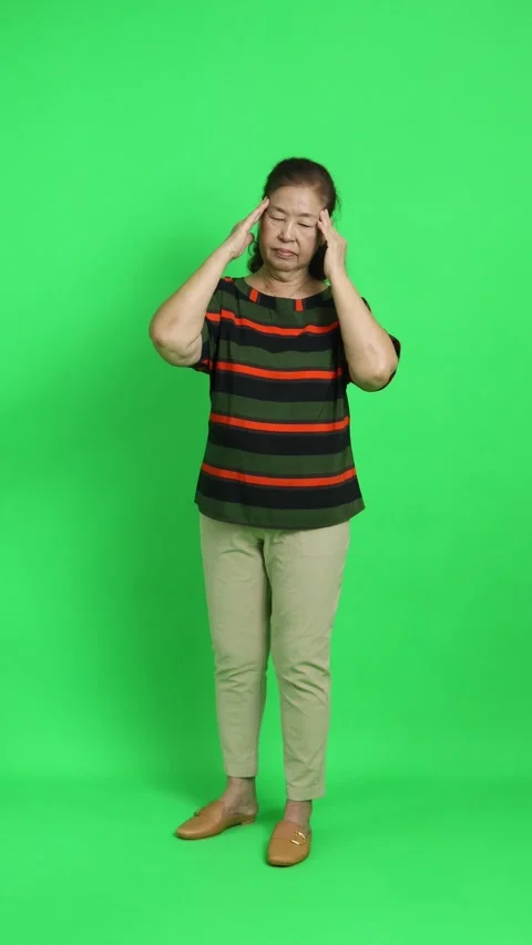 4K vertical shot of an elderly Asian woman massaging her temples, expressing str Stock Footage 342777505