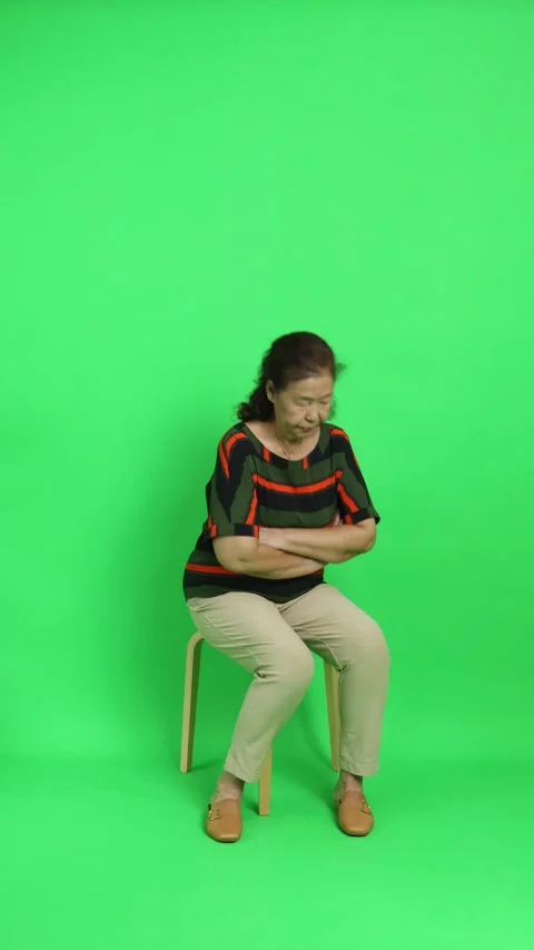 4K vertical shot of an elderly Chinese woman walking into the frame and sitting  Stock Footage 342777589