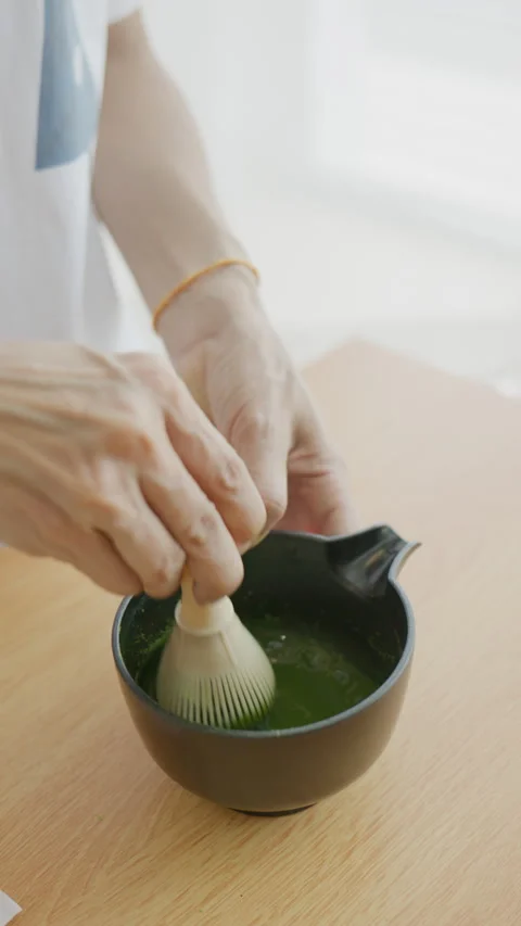 4K Vertical shot preparing traditional matcha green tea by whisking in a cup Stock Footage 340996344
