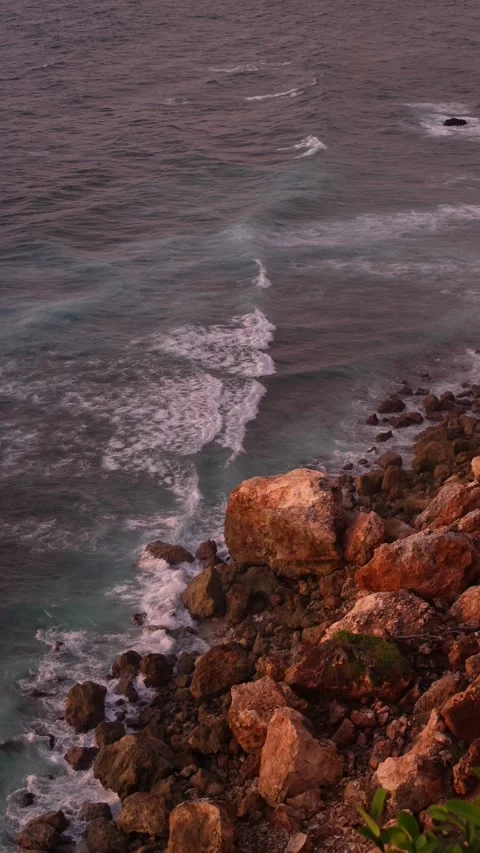 4K vertical slow motion of ocean waves crashing on cliffs at pink sunset 스톡 동영상 337085542