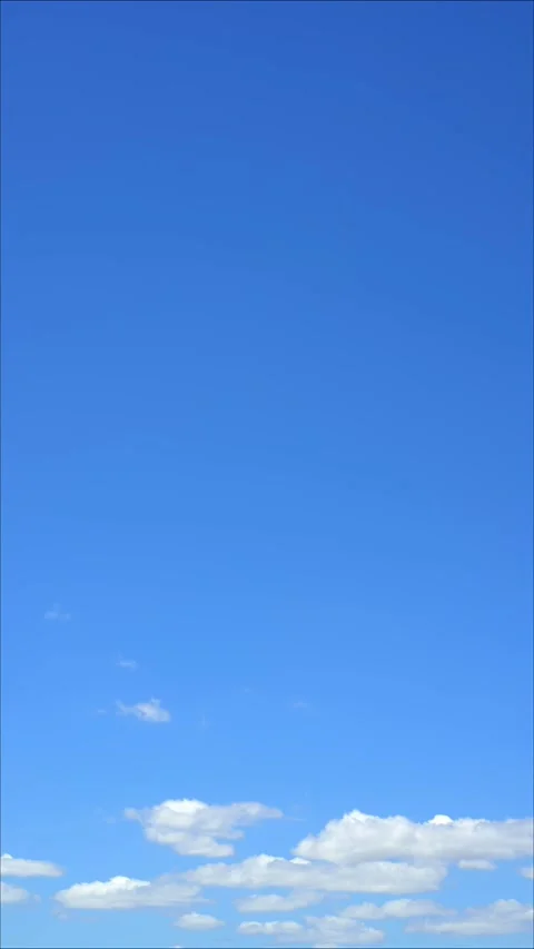4K vertical time lapse of white clouds drifting across bright blue sky Stock Footage 329011752
