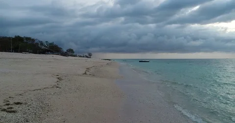 4K Very low flyover of lapping waves on indonesian coral beach with storm clouds Stock Footage 81687083