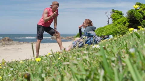 4K video of backpackers couple resting on Chamomile field on Atlantic ocean rock Stock-Footage 315474853
