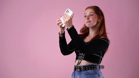 4k video of cute girl using phone over pink background. Video stock 234311491