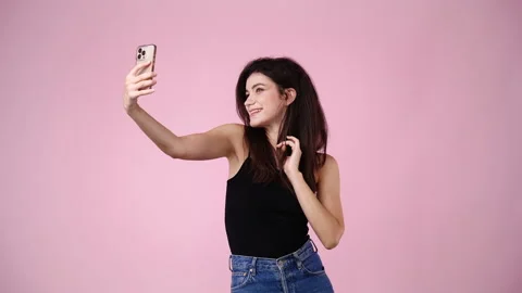 4k video of cute girl using phone and waving hello over pink background. Video stock 236415852