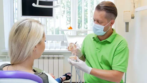 4k video of dentist explains teeth treatment to his patient on plastic jaw model Stock Footage 89389614