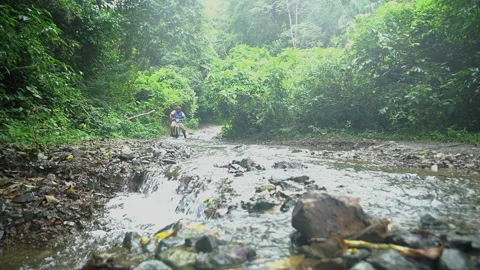 4k video of flooded backroads of Caribbean mountains with bike passing in slow. Stock Footage