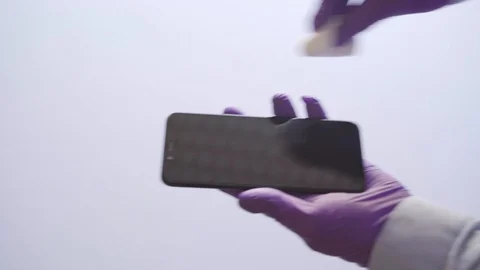 4k video of gloved hands cleaning a cell phone. Cleaning and hygiene concept Stock Footage 129603305