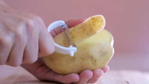 4K video of a hand using a vegetable peeler to peel a potato. Stock Footage 280830603