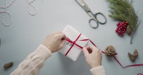 4K Video Hands Tying Red Ribbon on White Gift Box Open Me Tag Vídeo Stock 330423843