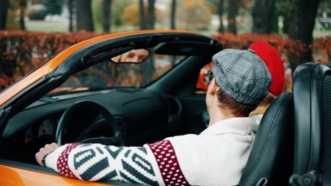 4K video: happy couple having fun while driving in orange cabriolet car. Autumn Stock-Footage 219623341