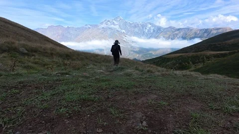 4k video of a hiker from behind walking down a mountain toward scenic peaks.. Stock-Footage 338239698