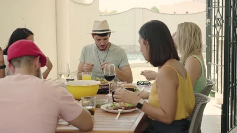 4K video of a latin man in a hat eating with friends Stock Footage 220159754