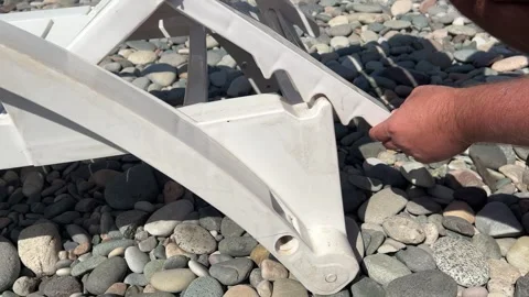 4K video. Man changes, sets height, tilt of backrest of plastic sun lounger Video stock 332878160