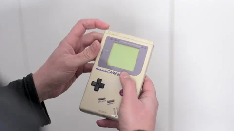 4k video of a man holding a classic video game console, Nintendo Game Boy Stock Footage 175181978