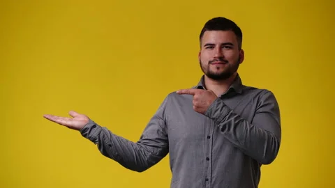 4k video of man pointing at left and showing thumb up over yellow background. Stock Footage 240088394